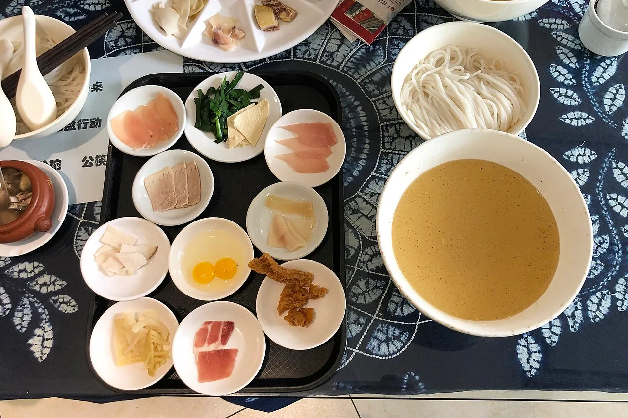 Kunming crossing-the-bridge rice noodles with side plates of raw ingredients