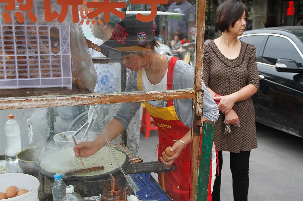 A morning jianbing guozi vendor cooking on a round griddle in Tianjin
