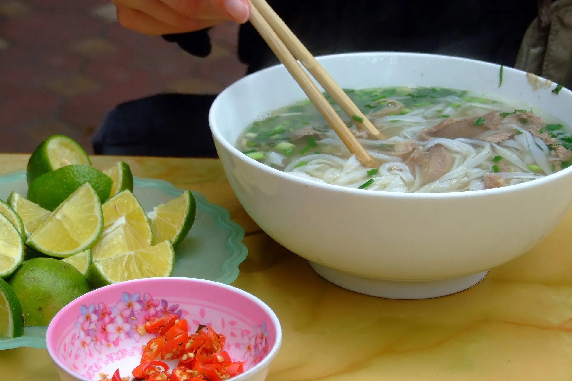 A bowl of Hanoi pho bo — clear beef broth, flat rice noodles and thin slices of beef
