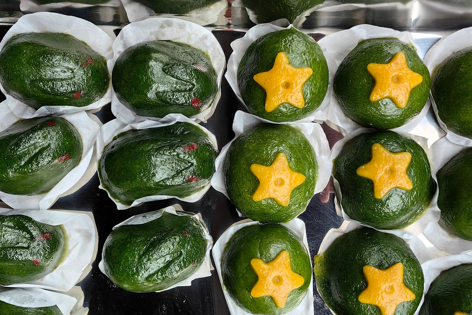 A tray of green qingtuan rice balls, some marked with a yellow star