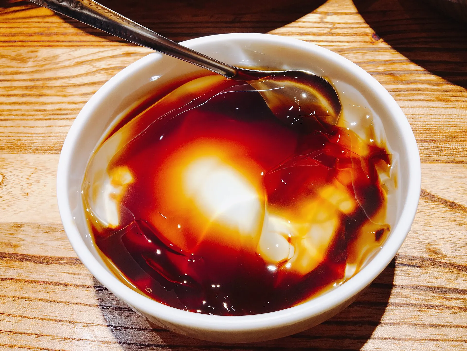 A bowl of brown-sugar bingfen — translucent ice jelly under dark brown-sugar syrup