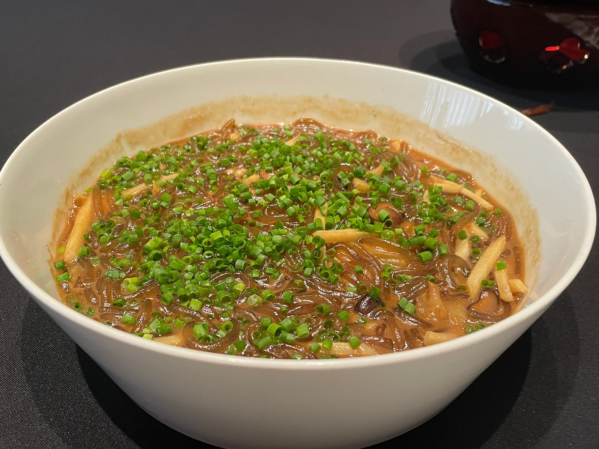 Sea-anemone bean noodles (沙蒜豆面) — springy bean-starch noodles in a savoury braise, topped with chopped chives, served at Xin Rong Ji