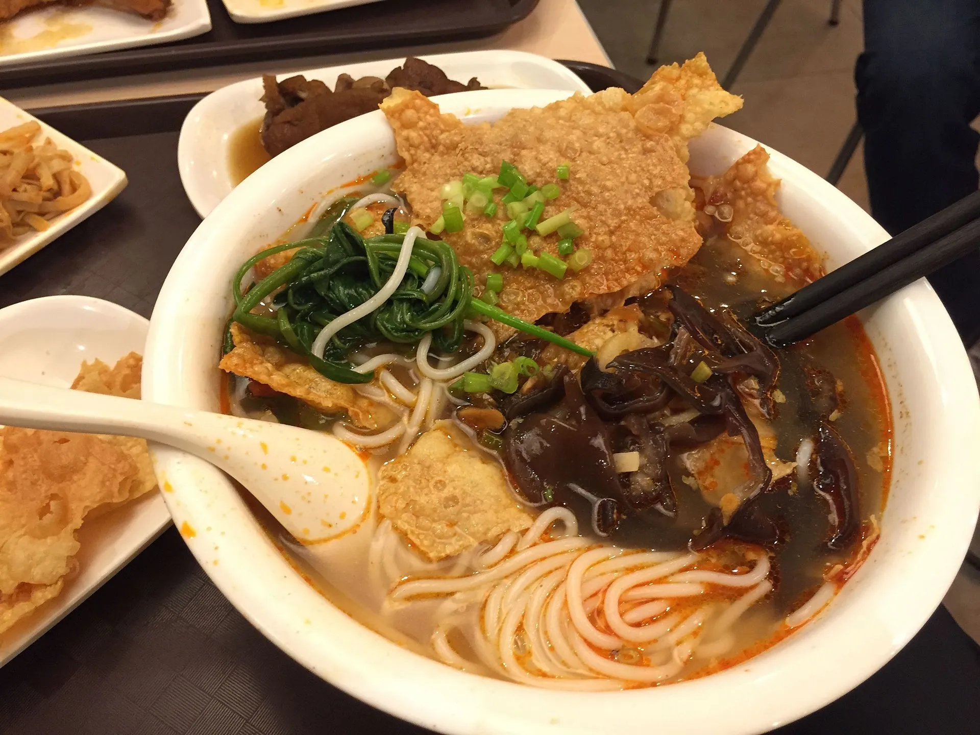 A bowl of luosifen — rice noodles in a dark, oily snail broth