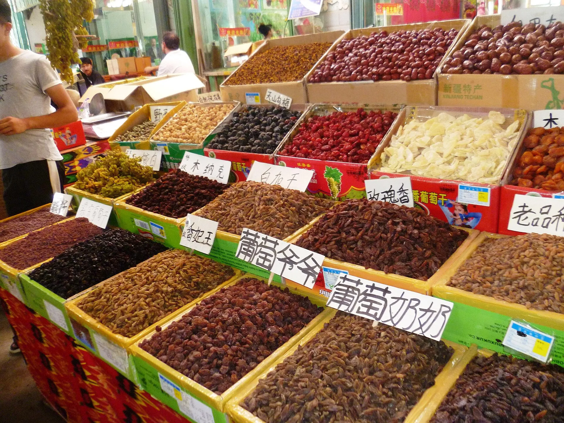 Rows of open bins piled high with many colourful varieties of raisins, dates and dried fruit at a Turpan bazaar