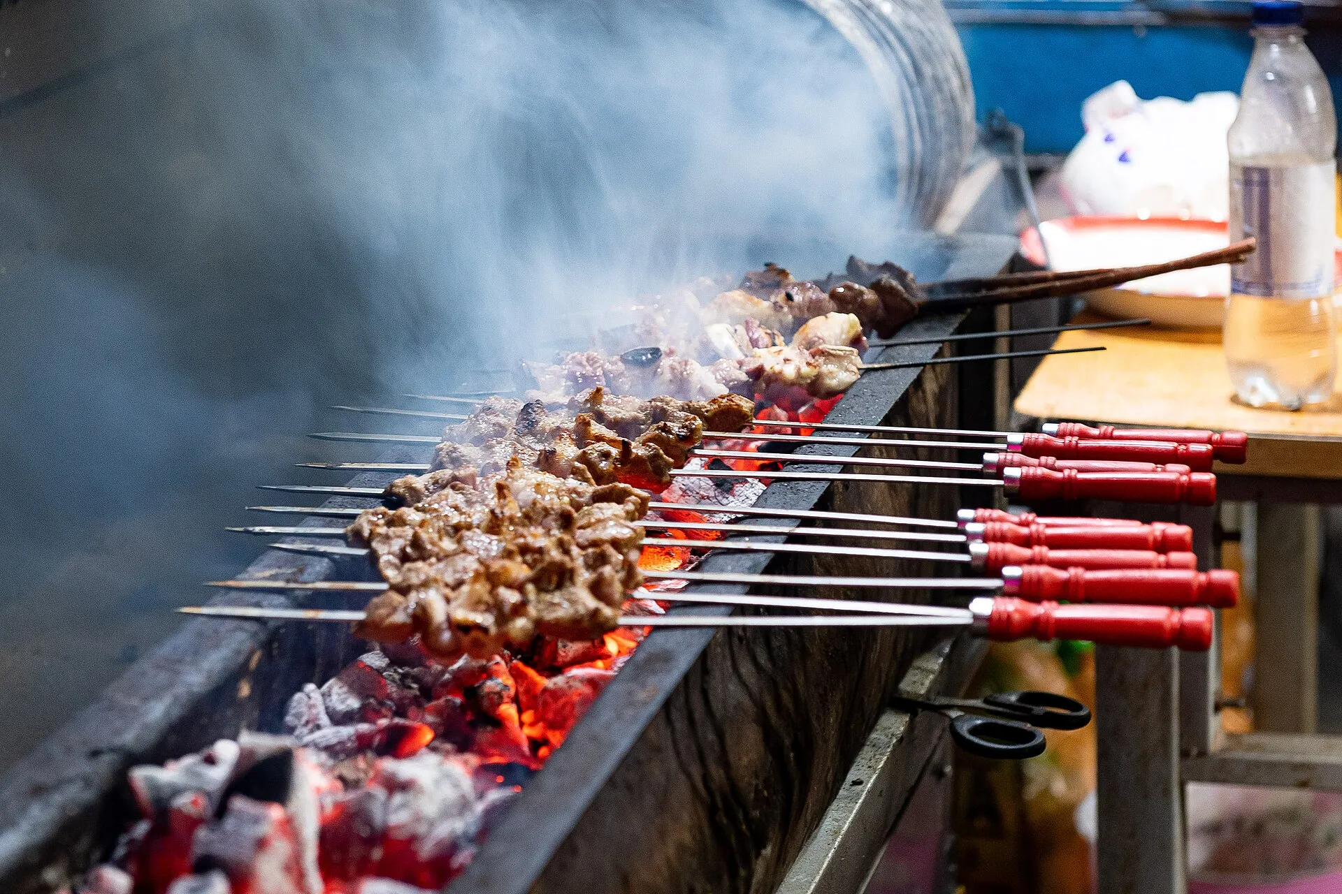 Cumin-spiced lamb skewers grilling over a long charcoal trough at a Kashgar street stall
