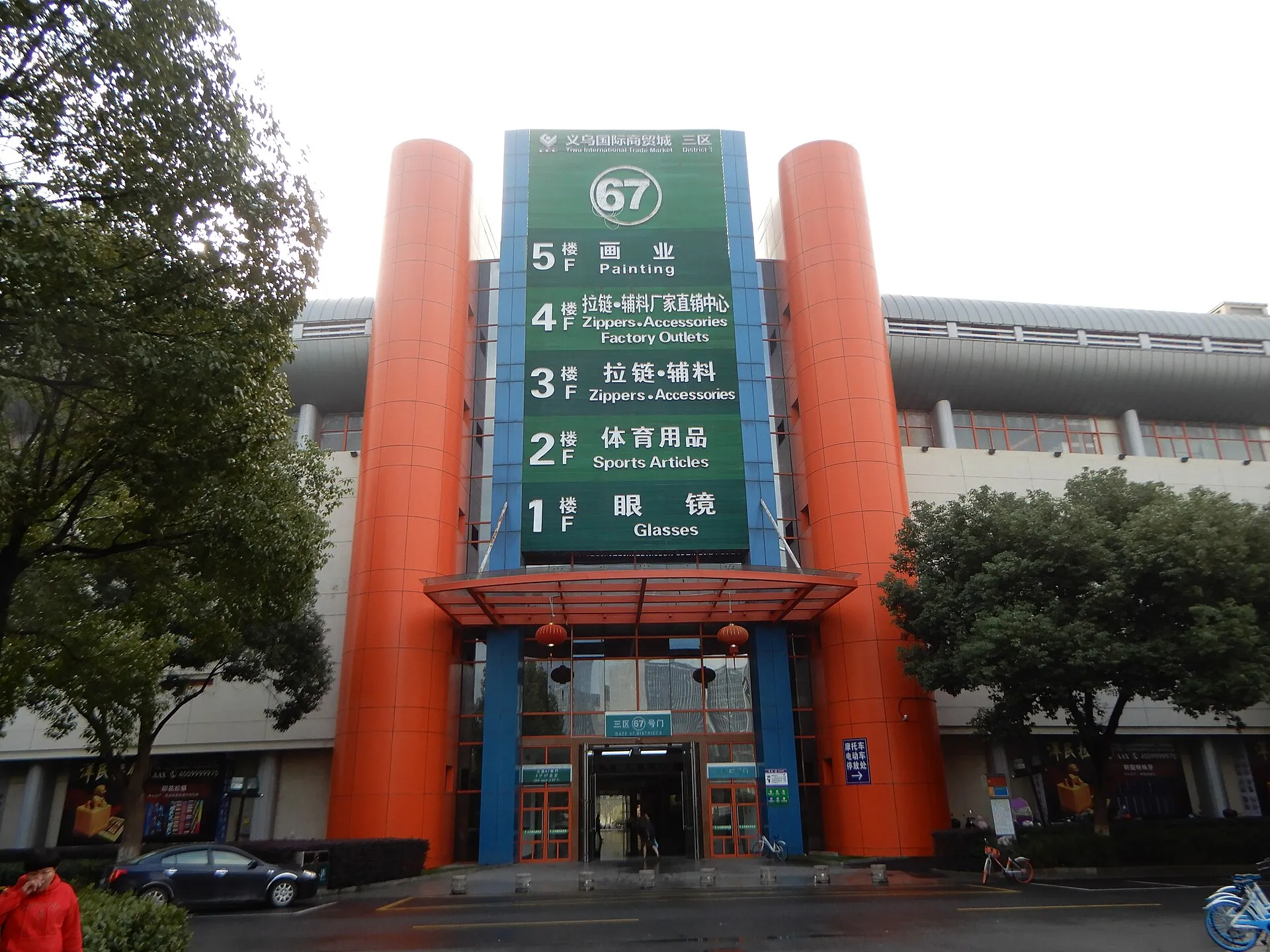 An entrance gate at Yiwu International Trade Market, its directory listing a different category of goods on each floor — glasses, sports articles, zippers and more